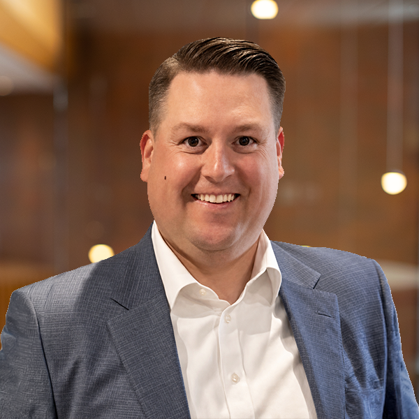 Professional headshot of a smiling man in a blue suit jacket in a modern office setting.